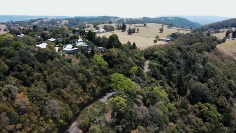 Drohnenantenne-über-Einem-üppigen-Australischen-Berg-Mit-Bäumen,-Häusern-Und-Einer-Straße