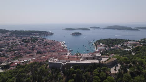 Aerial:-Fortica-Fortress,-Hvar,-Croatia-overlooking-harbor-and-islands