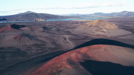 Aerial:-Reverse-reveal-of-dormant-and-vibrant-red-and-black-volcano-on-a-clear-day-in-Iceland-highlands