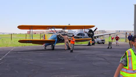 Pilot-of-a-Boeing-Stearman-75-vintage-world-war-II-training-aircraft-rotating-the-prop-before-starting-the-engine-at-an-airshow-at-the-Centennial-Airport-in-Colorado