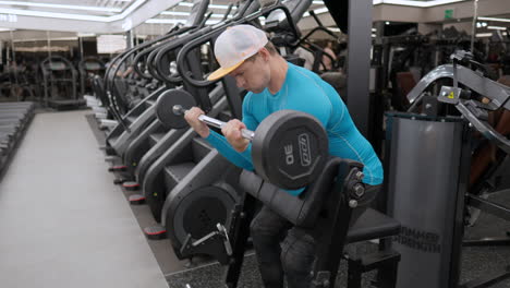 Man-training-arms-doing-Scott-barbell-biceps-curls-at-modern-gym