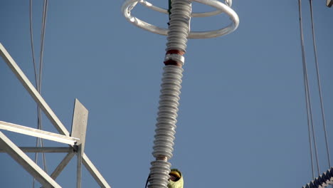 Tilt-down-Reveal-Of-Linemen-Working-On-Insulation-String-Of-Transmission-Tower