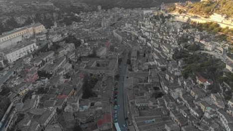 Flying-over-historic-town-of-Modica-Sicily-during-sunrise,-aerial