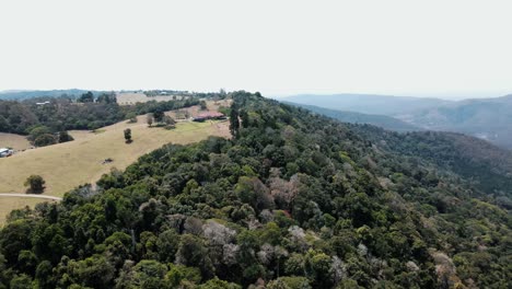 Drone-aerial-showing-contrast-between-cleared-land-on-a-mountain-and-a-lush-forest-in-Australian-national-parks