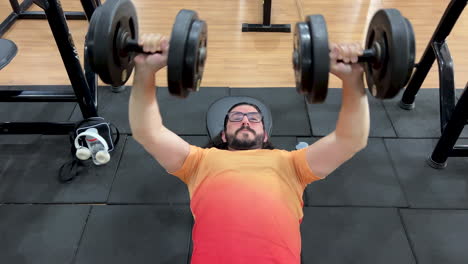 Latin-man-with-beard-and-long-hair-performing-bench-press-movement-with-dumbbell