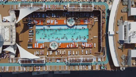 Cruise-ship-passengers-swimming-and-relaxing-on-lido-deck-pool-and-sun-lounge