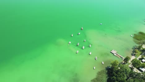 Tranquil-lakeside-beauty:-The-drone-unveils-Mondsee's-serene-waters,-with-boats-gently-swaying-at-a-rustic-wooden-pier
