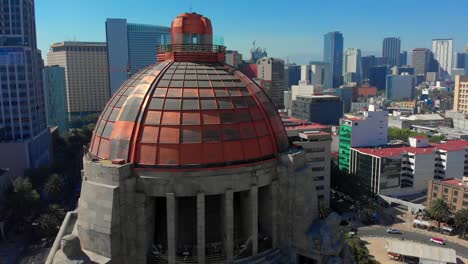 Drone-shot-of-revolution-monument-tall-buildings-back-Mexico-city-landscape-urban-daylight-blue-sky-warm-weather