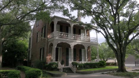 Historic-home-with-iron-fence-and-old-Southern-Live-Oak-trees-in-downtown-Mobile,-Alabama-with-gimbal-video-walking-forward-in-slow-motion