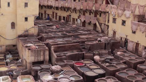 Panoramic-view-of-traditional-tanneries-in-Fes,-Morocco,-with-workers-using-ancient-methods-to-dye-animal-skins-in-different-colours
