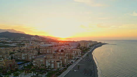 scenic-golden-orange-sunset-aerial,-evening-glow-drone-shot-on-beach,-Malaga-Spain