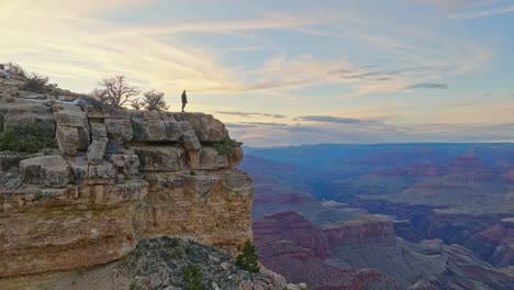 A-Man-Standing-on-Top-of-the-Grand-Canyon,-Arizona,-United-States---Aerial-Panning