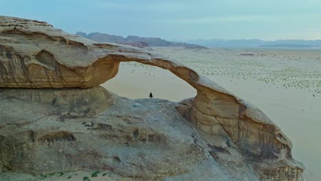 Luftaufnahme-Einer-Person,-Die-Durch-Den-Natürlichen-Bogen-Im-Wadi-Rum,-Jordanien,-Steht