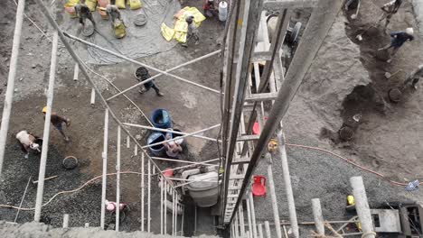Video-shot-from-above-of-construction-workers-preparing-concrete-material-at-the-construction-site-and-construction-manual-lift-lifting-concrete-on-the-floor-slab