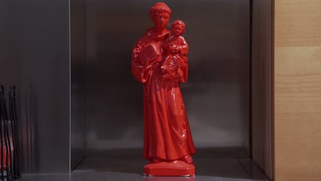 Rote-Statuette-Eines-Heiligen,-Der-Einen-Heiligen-Und-Ein-Buch-Hält