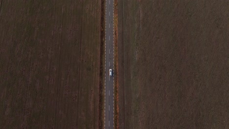 Drone-shot-captures-a-single-car-on-a-long,-straight-road,-evoking-a-sense-of-solitary-travel