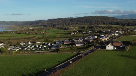 Aerial-view-orbiting-over-small-town-Welsh-community-farmland-with-Snowdonia-mountain-range-on-the-horizon