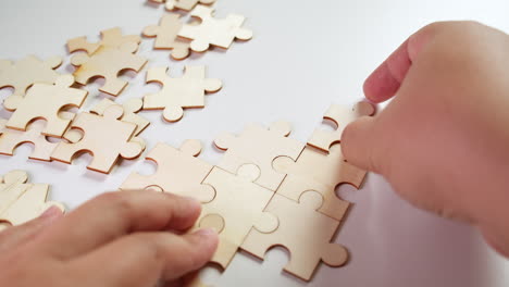 A-person-trying-to-solve-a-Jigsaw-Puzzle-without-pictures,-hand-holding-the-pieces-in-place-while-the-right-hand-adds-one-piece-after-another