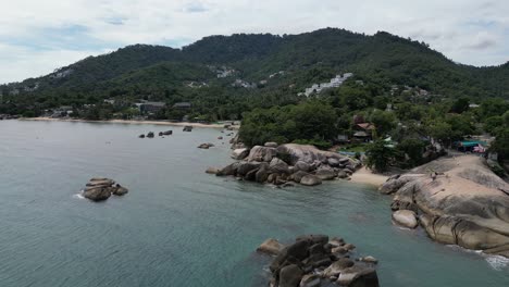 Zoom-in-aerial-shot-of-rocky-beaches-and-clear-blue-waters-in-Thailand