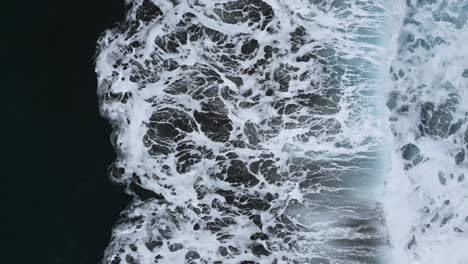 Slow-motion-aerial-view-of-the-sea-waves-breaking-on-the-shore