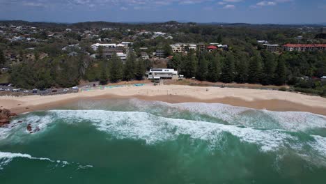 Turquoise-Ocean-And-Sandy-Shore-Of-Flynns-Beach-In-NSW,-Australia---aerial-pullback