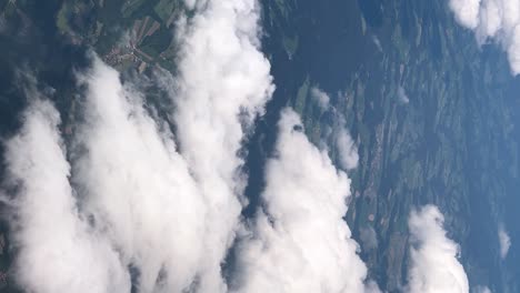 Vertikale-Rahmenaufnahmen-Fangen-Den-Faszinierenden-Blick-Auf-Dicke-Weiße-Wolken-Ein,-Die-Man-Durch-Ein-Flugzeugfenster-Im-Strahlenden-Tageslicht-Sieht