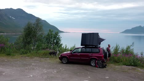 Camper-Standing-Next-To-SUV-With-Rooftop-Tent
