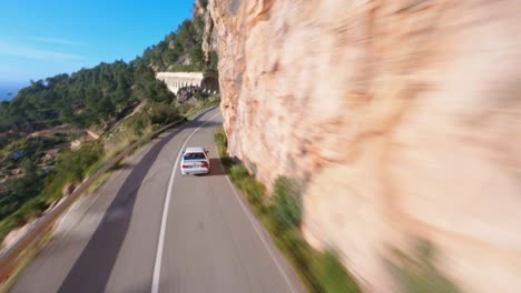 Drone-FPV-Volando-Rápido-A-Través-De-Túneles-Siguiendo-Un-BMW-Por-Una-Pintoresca-Carretera-Costera-De-Montaña-En-Mallorca
