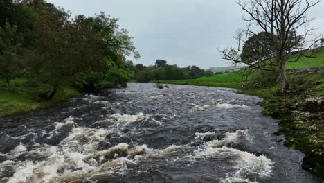 Slowly-tracking-forward-over-rapids-in-flowing-river,-Yorkshire,-United-Kingdom