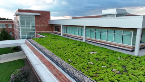 Modern-school-building-with-green-rooftop-garden,-large-windows,-and-brick-facade