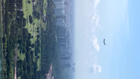 Atemberaubende-Stockaufnahmen-Aus-Der-Luft-Zeigen-Ein-Riesiges-Flugzeug,-Das-In-Richtung-Des-Flughafens-Von-Singapur-Fliegt,-Eingerahmt-Vom-Sand-Der-Marina-Bay,-Mit-Den-Wolkenkratzern-Und-üppigen-Gärten-Der-Stadt-Im-Hintergrund