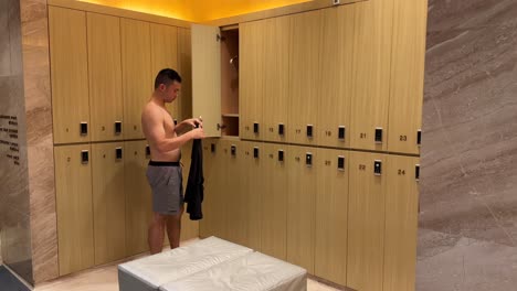 Asian-Millennial-Man-Wearing-Shirt-in-Luxurious-Changing-Room-in-a-High-End-Gym-Facility
