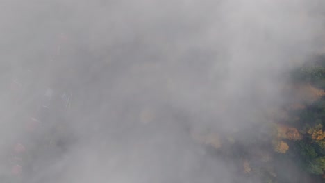Luftaufnahme-Von-Oben-Nach-Unten-über-Den-Lebendigen-Herbstlichen-Bergwald,-Gesehen-Durch-Wolken,-4k