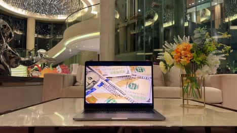 Laptop-Mit-100-Dollar-Scheinen-Auf-Dem-Bildschirm-Auf-Einem-Marmortisch-In-Einem-Luxuriösen-Herrenhaus