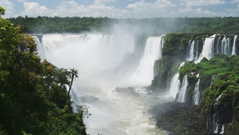 Cascadas-Brumosas-Y-Estrepitosas-En-Un-Río-Que-Fluye-Turbulento-Escondido-En-Un-Valle-En-Una-Jungla-Verde-Llena-De-Naturaleza,-Salpicando-Agua-De-Arroyos-Agresivos-Desde-Acantilados-En-Las-Cataratas-De-Iguazú,-Brasil,-América-Del-Sur