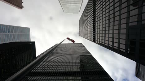 Canada-Flag-Waving-In-Wind-Surrounded-With-High-rise-Skyscrapers,-Toronto,-Canada