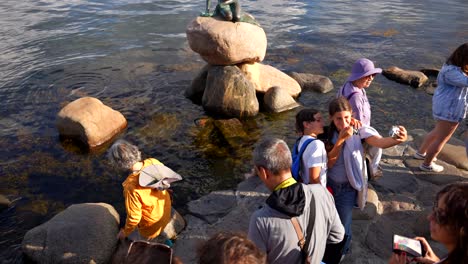 Kleine-Meerjungfrau-Statue-Auf-Einem-Felsen-Im-Wasser-Mit-Vielen-Menschen,-Die-In-Kopenhagen,-Dänemark,-Fotos-Machen
