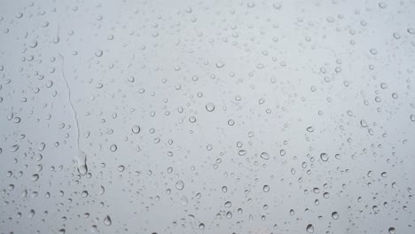 A-slow-motion-close-up-footage-of-heavy-rain-drops-is-seen-through-a-window-glass