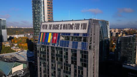 Putin-Den-Haag-Wartet-Auf-Sie.-Anti-Kriegs-Protestschild-Auf-Einem-Geschäftswolkenkratzer