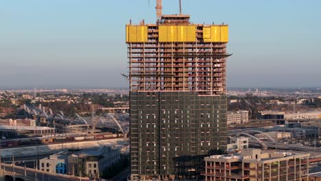 Skyscraper-construction-site-and-neighborhood-in-East-Los-Angeles---rising-aerial-reveal