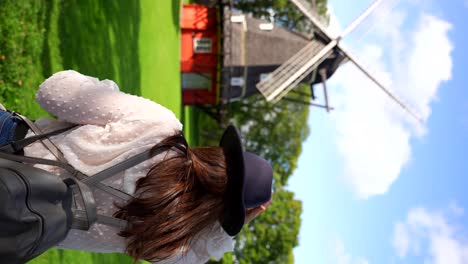 Woman-with-hat-and-backpack-looking-at-historic-windmill-in-Kastellet,-Denmark