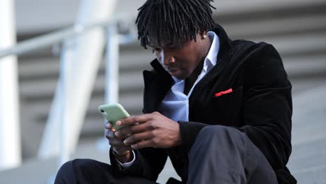 Young-African-Businessman-in-a-Black-Suit,-Taking-a-Call-on-Stairs