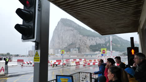 Menschen,-Die-An-Einem-Regnerischen-Tag-Am-Straßenübergang-Des-Flughafens-Von-Gibraltar-Warten