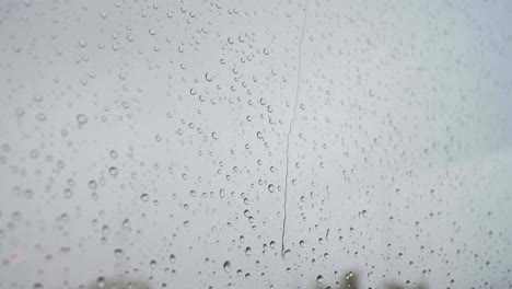 A-slow-motion-footage-of-a-close-shot-of-heavy-rain-drops-is-seen-through-a-window-glass
