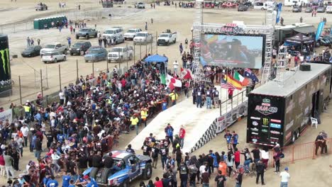 Rallye-Autofahrer-Spricht-Auf-Dem-Bildschirm,-Während-Die-Menge-Beim-Baja-500-Rally-Raid-Rennen-Zuschaut