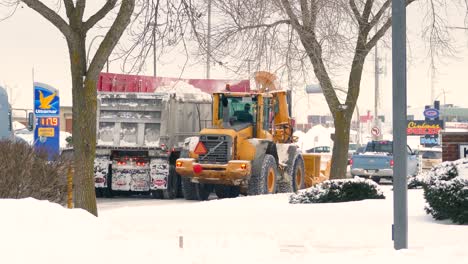 Bagger-Mit-Pflug-Bläst-Schnee-In-LKW-Anhänger,-Straßenreinigung-Und-Instandhaltung-In-Montreal,-Kanada