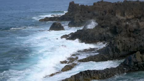 Close-up-shot-off-of-waves-crashing-and-water-splashing-on-the-volcanic-rock-coast-of-Lanzarote