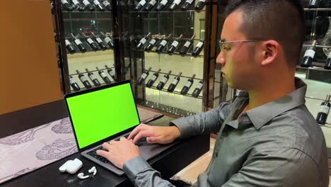 Asian-Millennial-Entrepreneur-Man-Typing-on-Laptop-with-Green-Screen-In-Luxurious-Home