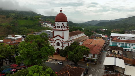 Aerial-view-rising-in-front-of-the-St-Raphael's-Church-in-cloudy-Antioquia,-Colombia