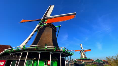 Low-angle-close-up-shot-of-windmills-with-blue-sky-in-the-background-in-Zaanse-Schans,-Netherlands
